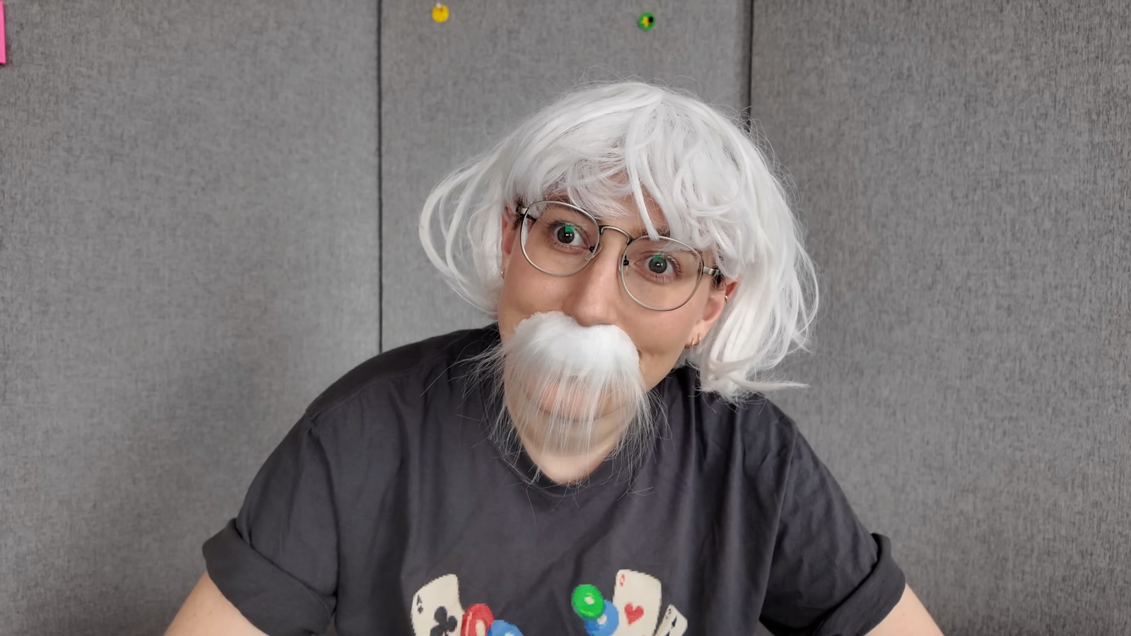 Alberta Tech in a white wig, glasses, and a white mustache, tilting her head